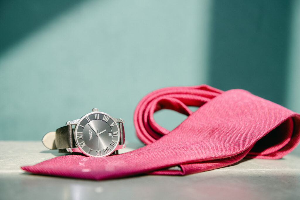 Groom's details wedding photograph showcasing a Tiffany & Co watch and a Scappino pink silk tie